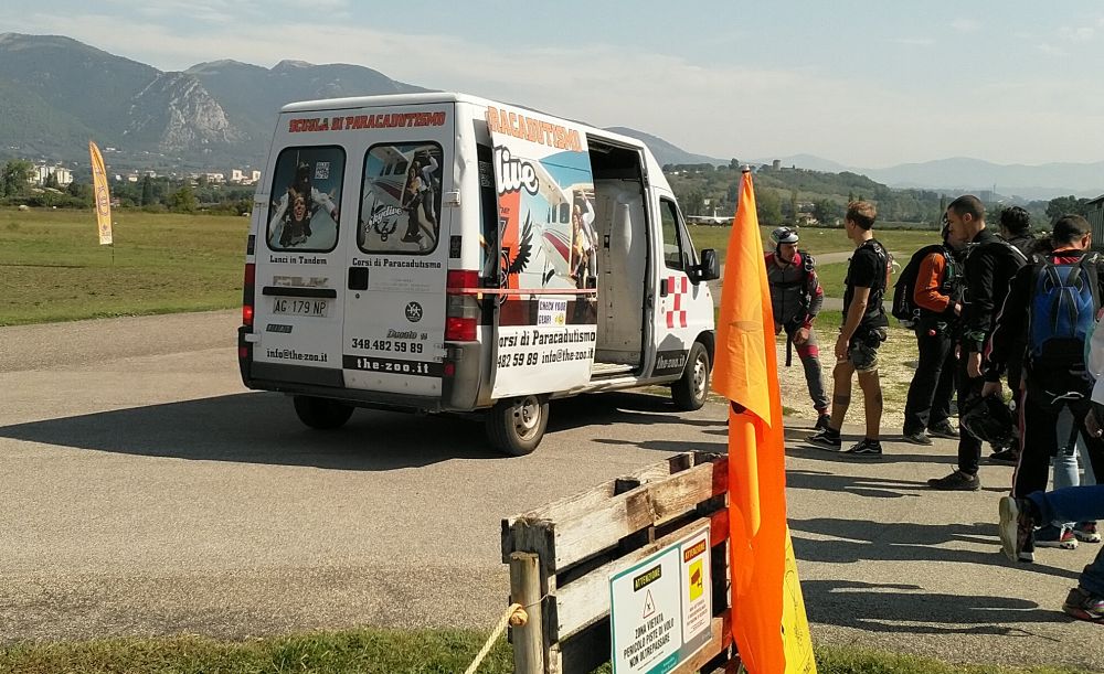 Ein Lieferwagen begleitet Tandem-Masters und Passagiere zum Flugzeug auf dem Fluggelände